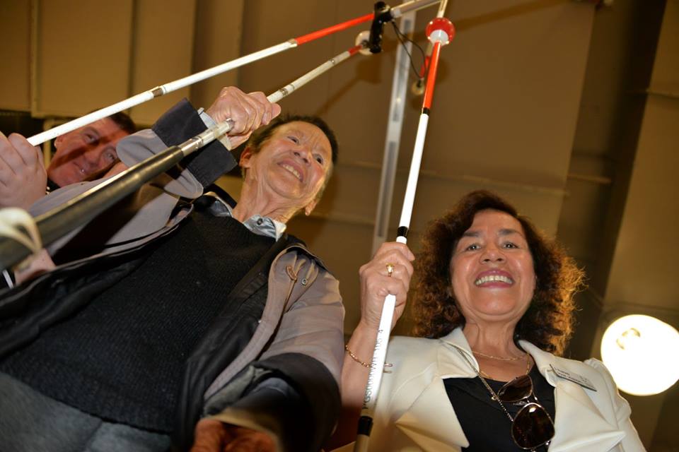 Three traveler indoors, pointing their white canes high above their heads