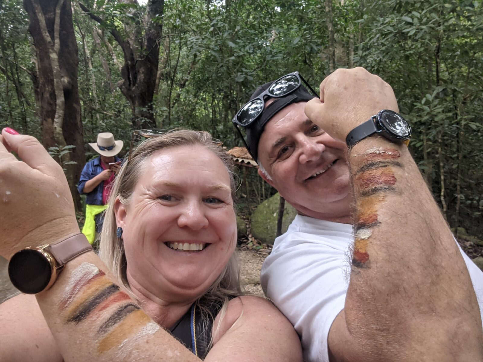 Donna next to traveller at Mossman Gorge with fists raised showing ochre paint on forearms